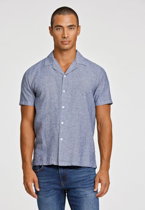 Korte mouwen shirt in lichtblauw linnenmengsel met een kraag, vijf knopen en subtiele textuur. Gecombineerd met donkere spijkerbroek.