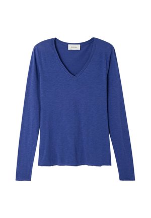 Zila V-veida izgriezuma krekls ar garām piedurknēm. Izgatavots no mīksta, viegla auduma ar brīvu pieguļojumu un nedaudz izliekta apakšmalu.