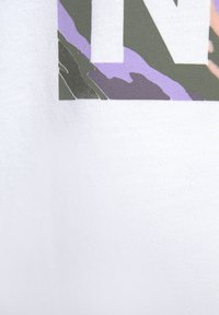 Weißer Stoff mit einem mehrfarbigen Druck, der grüne, lila und pfirsichfarbene Muster sowie fettgedruckten Text aufweist. Die Textur wirkt glatt und weich.