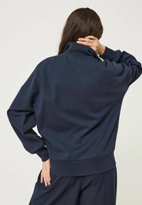 Pullover blu navy realizzato in tessuto morbido, con colletto alto, vestibilità comoda e polsini e orlo a coste. Adatto per l'abbigliamento casual.