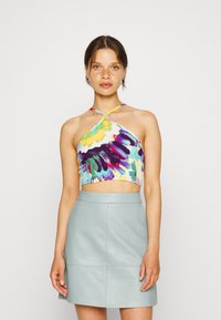 Top crop com um padrão floral colorido em amarelo, roxo e azul; design com tiras e decote halter. Combinado com uma saia de couro azul claro.