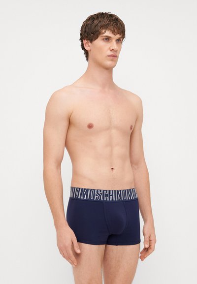 Námořnické modré bavlněné boxerky s širokým elastickým páskem, na kterém je bílý nápis "Moschino". Přiléhavý design s hladkým povrchem.