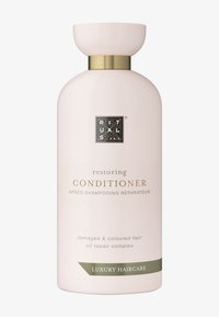 Lichtroze fles met een ronde body, gouden accent bij de hals en zwart logo. Het etiket bevat "herstellende CONDITIONER" en gebruiksdetails.