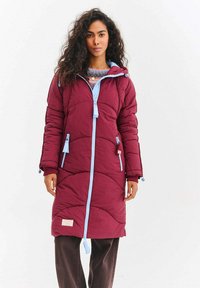 Bordový zateplený kabát s modrým zipem a šňůrkami, s prošívanou strukturou, bočními kapsami a délkou po kolena.