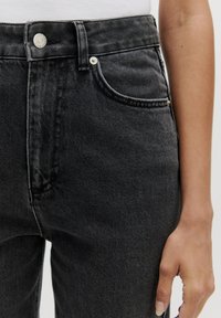 Hoge taille zwarte denim jeans met een klassiek vijfzakkenontwerp, subtiele vervaging, zilveren hardware en een gestructureerde stofafwerking.