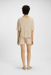 Beżowy zestaw odzieży domowej składający się z luźnej bluzki z krótkim rękawem i szortów. Miękka, teksturowana tkanina, charakteryzująca się swobodną sylwetką.