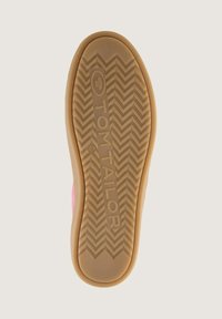 Gummisula med ett fiskbensmönster i ljusbrunt, märkt "TOM TAILOR" i mitten, kantad med en rosa textilöverkant.