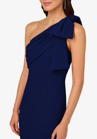 Námořnická modrá, jednoramenná šaty vyrobené z hladké látky. Obsahuje draped design s velkým mašlí na rameni. Elegatní silueta.