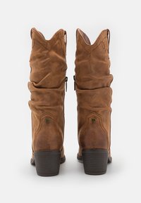 Botas de cuero marrón hasta la rodilla con un diseño arrugado, que presentan un borde superior en ángulo, cremallera lateral y un tacón apilado.