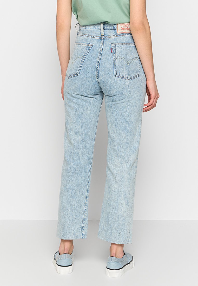 Jean taille haute bleu clair en denim, avec une coupe droite, deux poches arrière et une étiquette en cuir avec la marque à la taille.