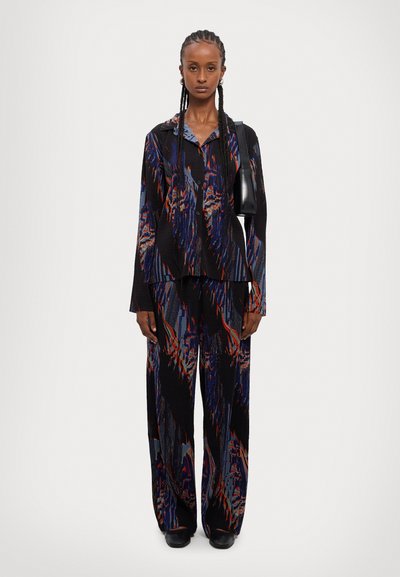 Fekete és színes mintázatú kétrészes szett, amely tartalmaz egy gombos inget és széles szárú nadrágot, könnyű anyagból, texturált felülettel.