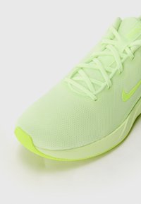 Hellgrüner Sportschuh mit Mesh-Obermaterial, flachen Schnürsenkeln, gepolsterter Sohle und markanten strukturierten Details an den Seiten und der Zehenpartie.