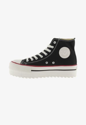 Zapatillas altas negras con cordones blancos, puntera de goma y suela de plataforma a rayas. Presentan un parche con el logo y costuras en contraste.