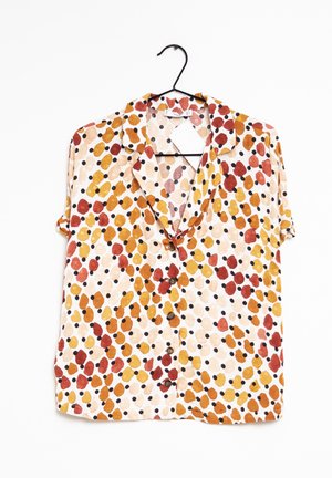 Kortærmet skjorte med knapper med røde, orange og gule abstrakte pletter samt sorte prikker, hængende på en sort bøjle.