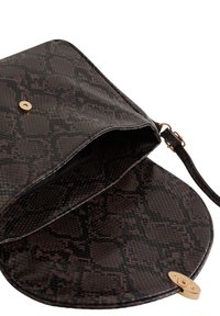 Brun imitativ läder crossbody-väska med ett texturerat ormskal, som har ett guldigt tryckknäpplås och en justerbar rem. Öppen insida synlig.