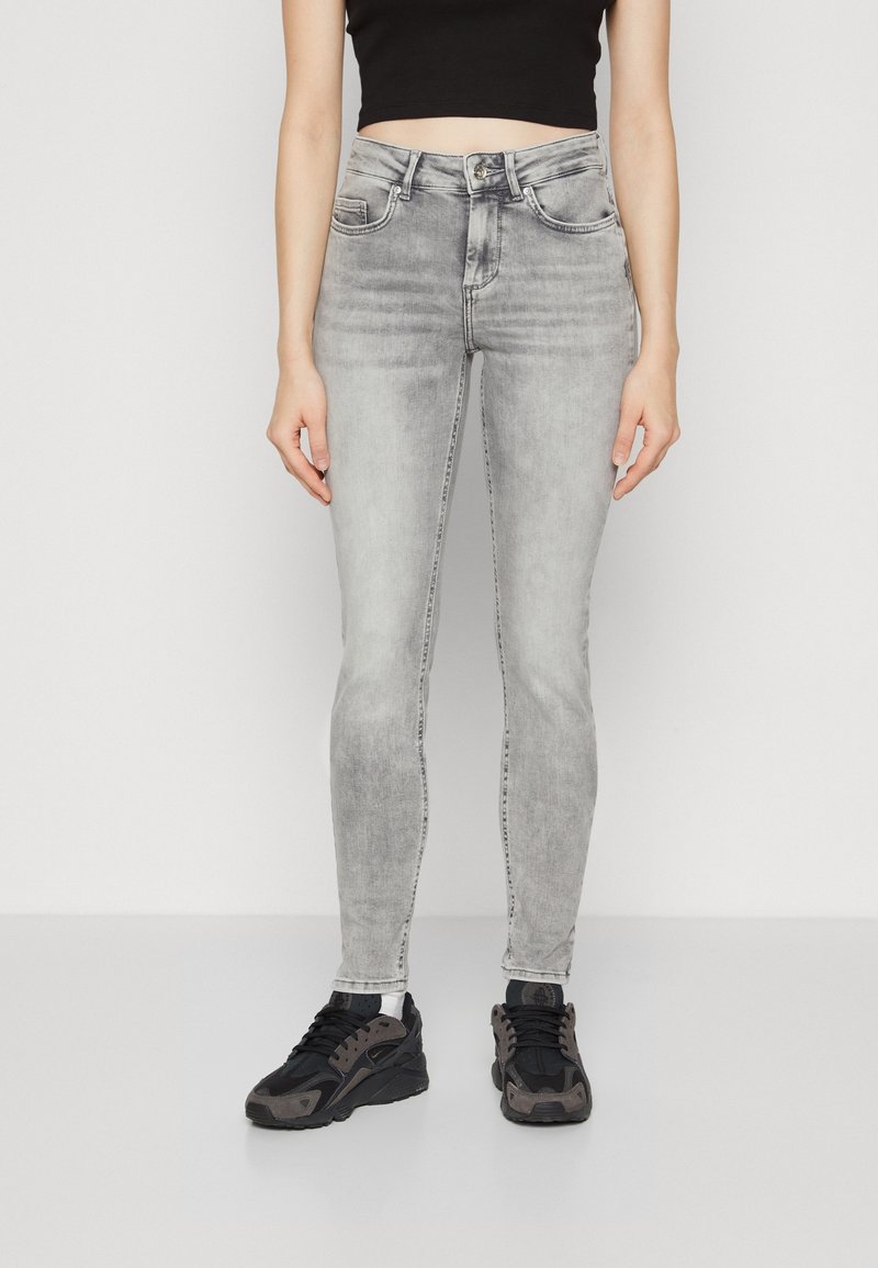 Jeans ajustados de talle alto en color gris, fabricados en denim, con diseño de cinco bolsillos, trabillas para cinturón y cierre de cremallera con botón.