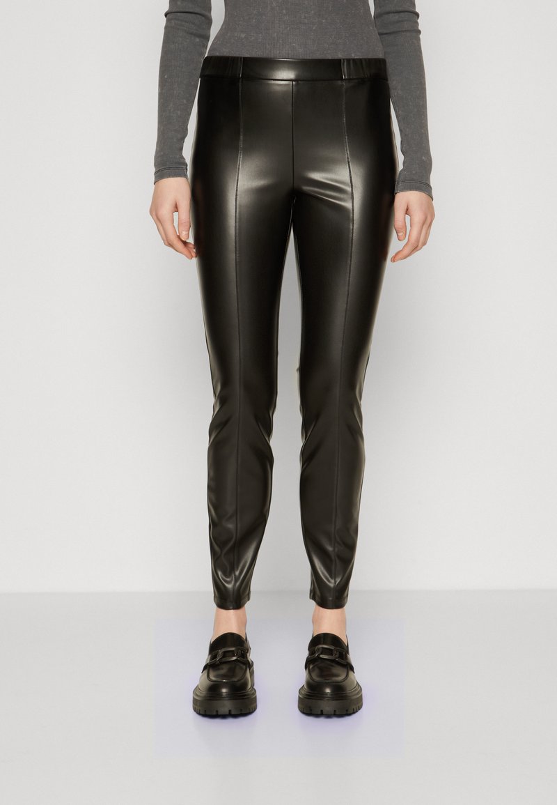 Black faux leather leggings with a slim fit, featuring a high waist and sleek finish, paired with black chunky loafers.