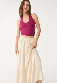 Musta halterneck crop top, joka on yhdistetty vaaleanbeigeen kerrokselliseen maksihelmaan, jossa on joustava vyötärö ja joka on valmistettu kevyestä kankaasta.