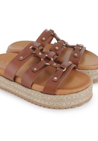 Sandalias deslizantes de cuero marrón con un diseño de múltiples correas, herrajes en tono dorado y suela tipo cuña de yute. Textura suave, estilo casual.