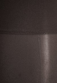 Ogenomskinligt svart tyg med en slät textur, har en horisontell söm som delar två texturer: en ribbad och en silkeslen.