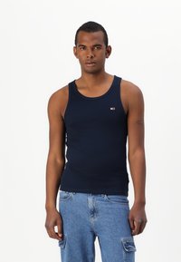 Marineblå tanktop laget av bomull, med rund halslinje og smal passform, samt et lite logomerke på venstre bryst.