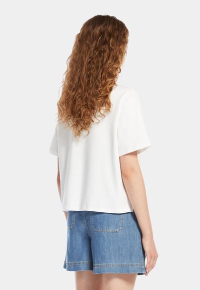Top alb cu maneci scurte, cu o croială relaxată, fabricat dintr-un material moale. Asortat cu pantaloni scurți din denim, cu un croi clasic și buzunare la spate.
