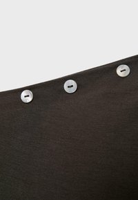 Tamni materijal s tri ravnomjerno raspoređena sjajna okrugla gumba ušivena u vodoravnom redu blizu ruba.