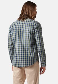 Camisa de manga larga con un patrón de cuadros verde y azul, hecha de tela tejida. Presenta un dobladillo curvado y puños abotonados.