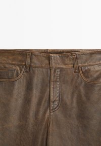 Brown leather pants with belt loops, front zipper, and two front pockets, shown from the waist to the upper thigh area.