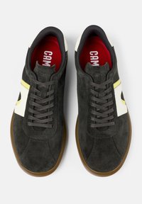 Dunkelgraue Wildledersneaker mit weißen und gelben Akzenten. Verfügt über ein Schnürdesign und eine braune Gummisohle. Rote Innenauskleidung.