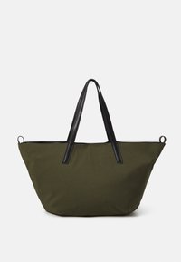 Olivgrüne Canvas-Tasche mit schwarzen Ledergriffen und -verzierungen, die eine breite Öffnung und eine glatte Textur aufweist. Zwei Seiten-Schlaufen zur Befestigung.