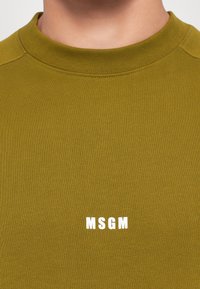 Oliivivihreä puuvillainen crewneck-huppari, jossa on ribbireunus kauluksessa. Etupuolella valkoinen "MSGM"-logo printattuna. Pehmeä rakenne, rento muotoilu.