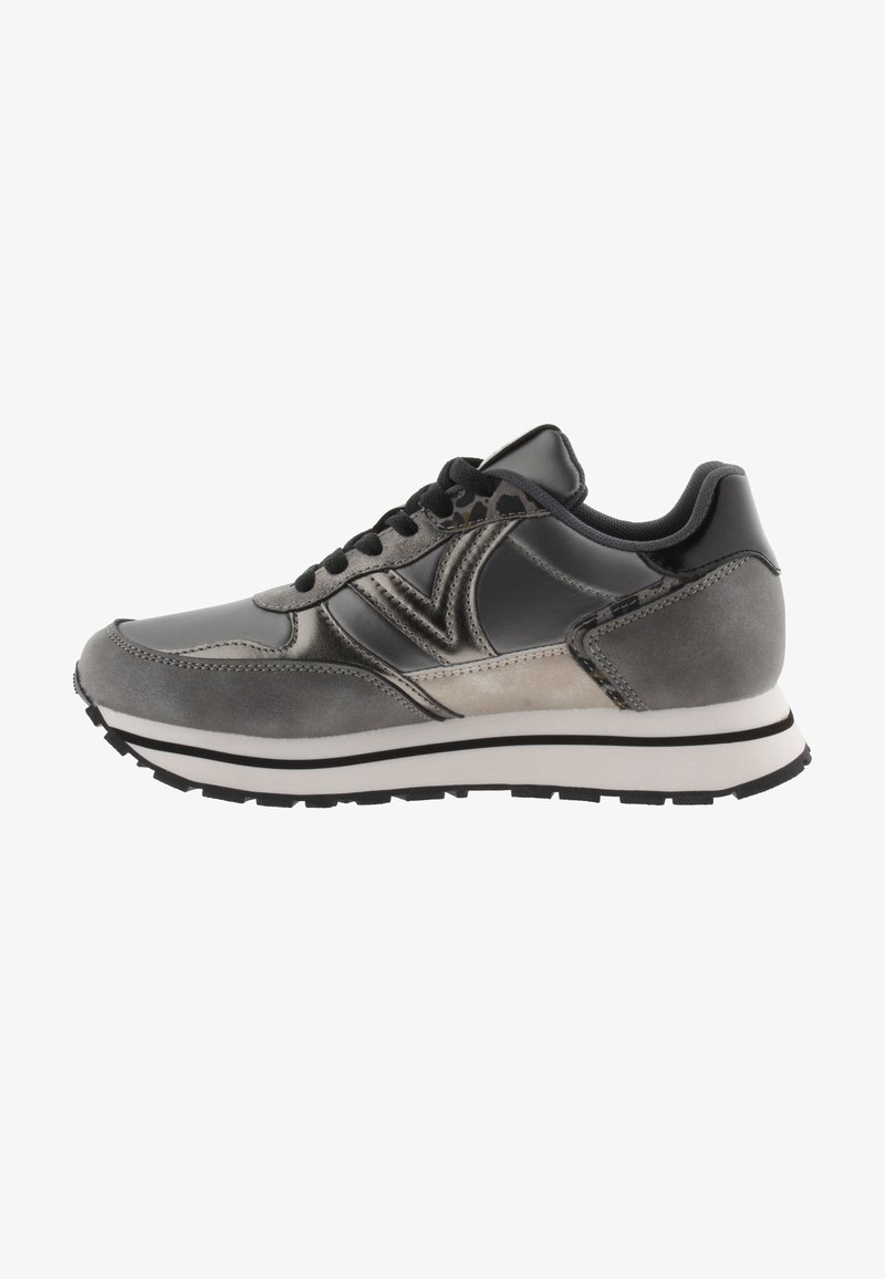 Zapato deportivo gris que presenta una combinación de materiales lisos y texturizados, una forma redondeada, cordones negros y una suela media blanca con acentos negros.