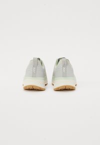 Baskets de sport vert clair avec une tige en maille texturée et des semelles en caoutchouc. Elles possèdent un talon renforcé et un marquage minimal à l'arrière.
