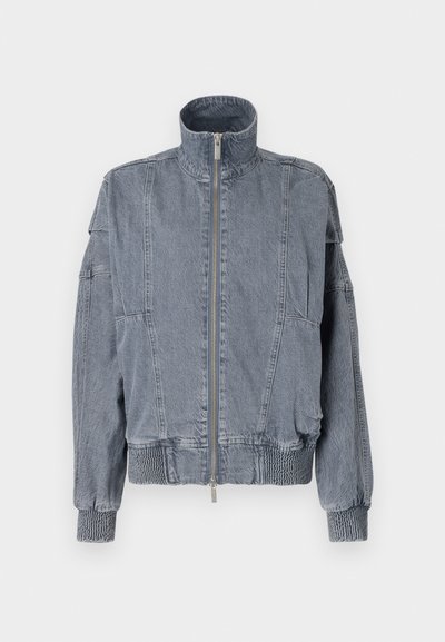 Jachetă din denim de culoare albastră deschisă, cu guler înalt, fermoar frontal, talie elastică și manșete texturate. Are un design aplicat și buzunare laterale.