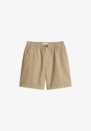 Beige casual shorts with elastic waistband, front button, belt loops, side pockets, and a label inside the waistband.
