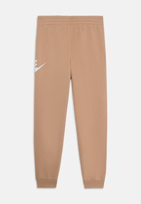 Beige sporta bikses ar elastīgu jostasvietu, pieguļošiem piedurkņu galiem un izteiksmīgu baltu Nike logo kreisajā augšstilbā. Audums šķiet gluds un viegls.
