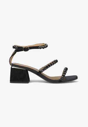 Czarna sandał z szerokim obcasem blokowym, z trzema paskami ozdobionymi czarnymi ćwiekami. Gładka skóra na górze i wyściełana wkładka.
