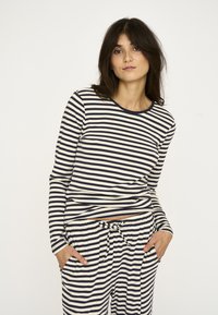 Langærmet trøje og bukser i creme med marineblå vandrette striber, med rund halsudskæring og lommer i bukserne.