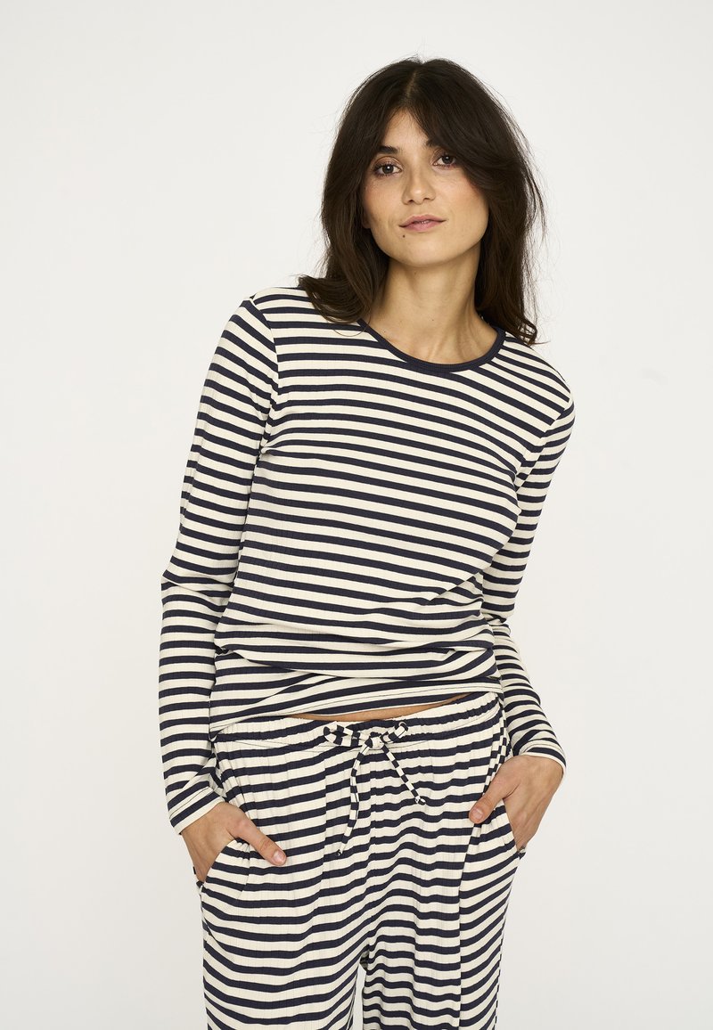 Langærmet trøje og bukser i creme med marineblå vandrette striber, med rund halsudskæring og lommer i bukserne.