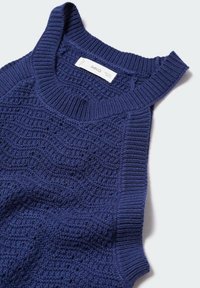 Marinblå stickad ärmlös topp med ett texturerat mönster, ribbad halsringning och ärmhål, med en sydd etikett som visar varumärkesnamnet.