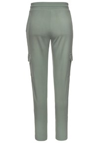 Hellgrüne Cargo-Hosen mit glatter Textur, elastischem Bund und Taschen an den Seiten. Das schmal zulaufende Bein bietet eine enganliegende Passform.