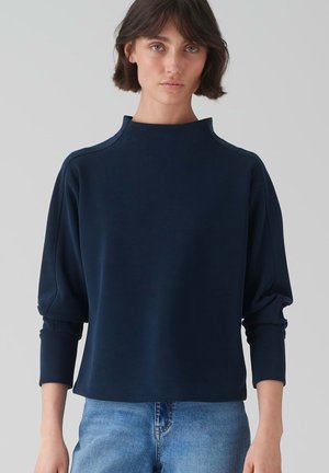 Marineblaues Pullover-Oberteil mit hohem Kragen, überschnittenen Schultern und langen, gerafften Ärmeln. Hergestellt aus weichem Stoff mit lässiger Passform.