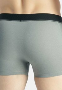 Boxers briefs pour hommes gris avec une taille côtelée noire. Texture lisse avec une coupe ajustée, conçue pour le confort et le soutien.