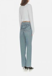 Jeans in denim blu chiaro con un design unico della tasca posteriore, abbinati a un top bianco a maniche lunghe cropped, con texture liscia e vestibilità dritta.