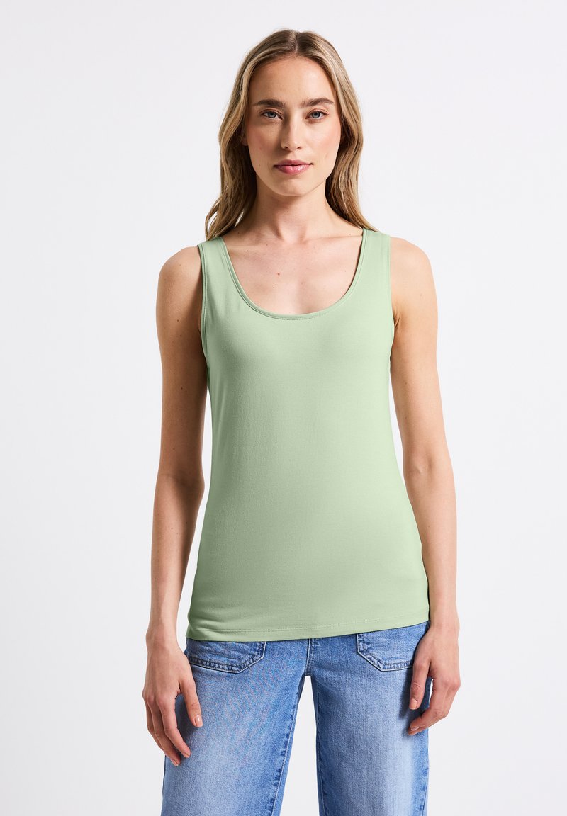 Top senza maniche verde chiaro con scollatura rotonda e spalline larghe, realizzato in un tessuto morbido ed elasticizzato. Abbinato a jeans in denim blu.