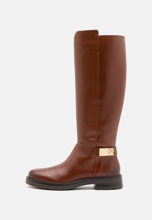 Botte haute en cuir marron avec un design élégant, semelle en caoutchouc plate et accent métallique doré sur le côté. Texture lisse sur toute la surface.