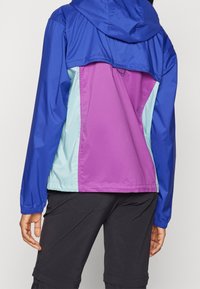 Colorful jacket featuring blue, purple, and light green panels. Lightweight material with a hood and elastic cuffs, designed for active wear.