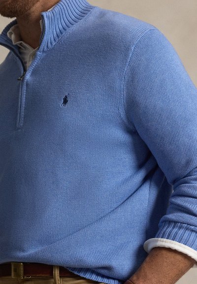 Φωτεινό γαλάζιο πλεκτό πουλόβερ με ριμπ γιακά και φερμουάρ στο ένα τέταρτο. Κεντημένο λογότυπο στο αριστερό στήθος. Απαλή υφή.