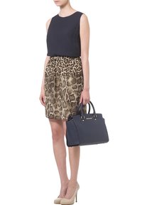 Marinblå ärmlös topp, leopardmönstrad kjol, ljusbeige klackskor och en strukturerad marinblå handväska med gulddetaljer. Väskan har dubbla handtag.